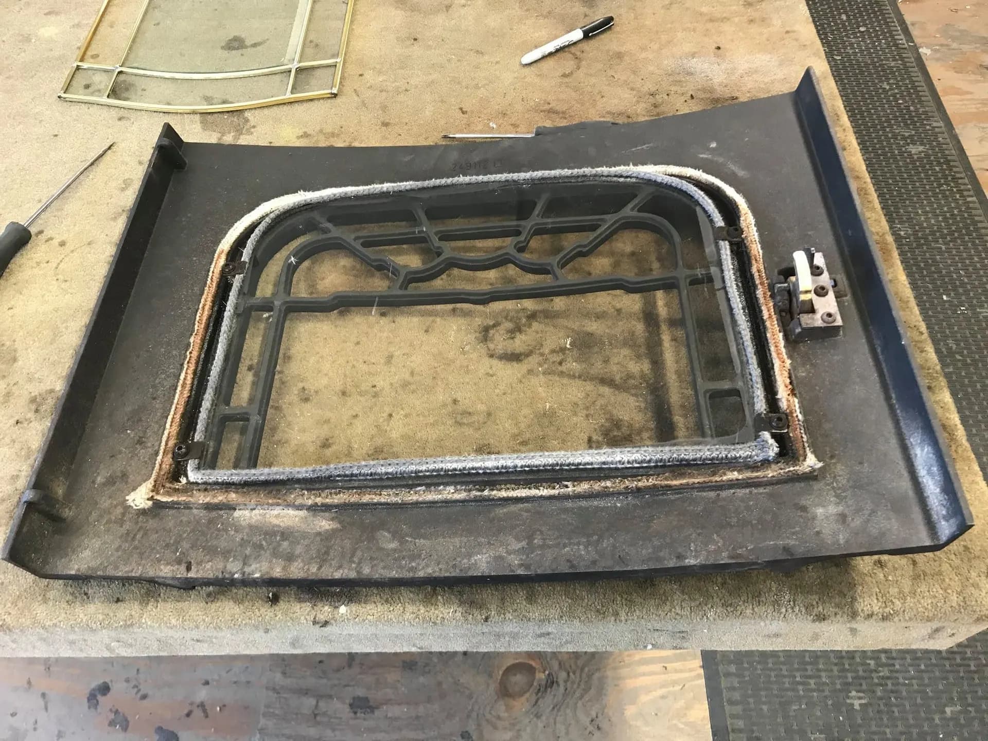 Car door with the glass removed on the workbench, exposing the window channel and weatherstrip.