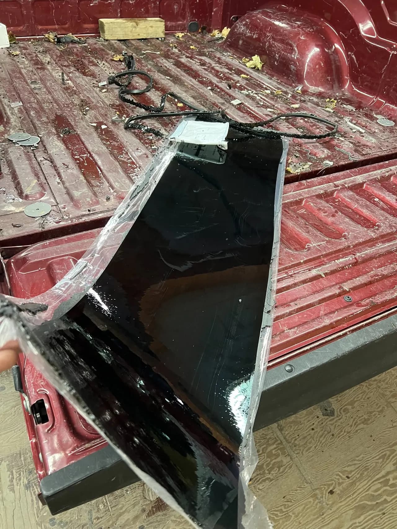 Tinted vehicle back glass laid in the bed of a red pickup truck during an auto glass replacement