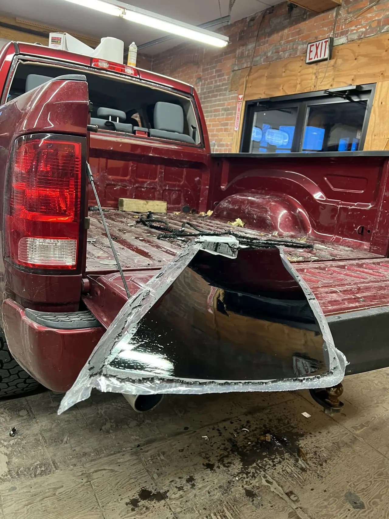 Pickup truck in the shop bay with its rear window shattered, waiting on new back glass