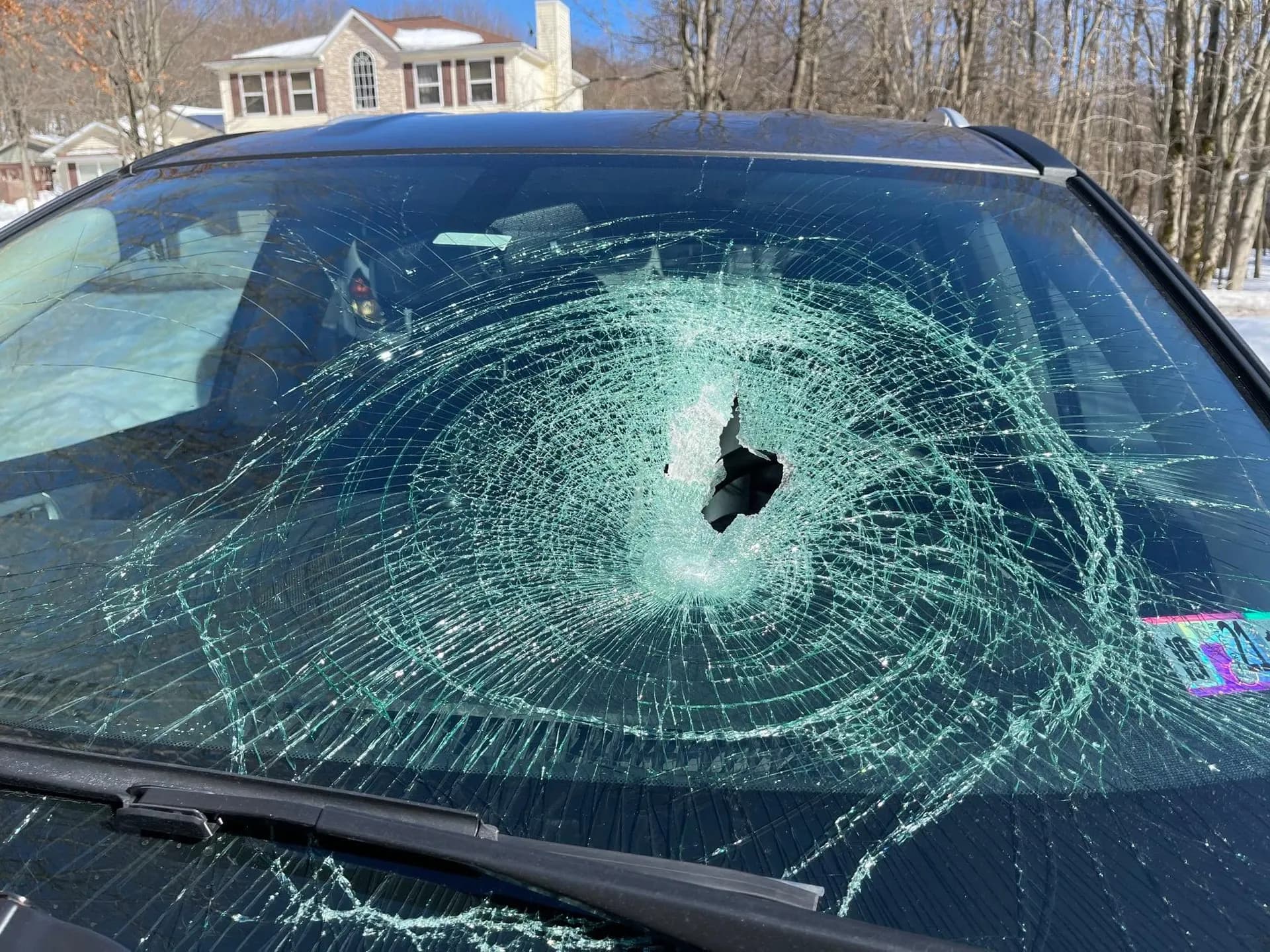 Windshield with a fist-sized impact hole and cracks running the full width of the pane
