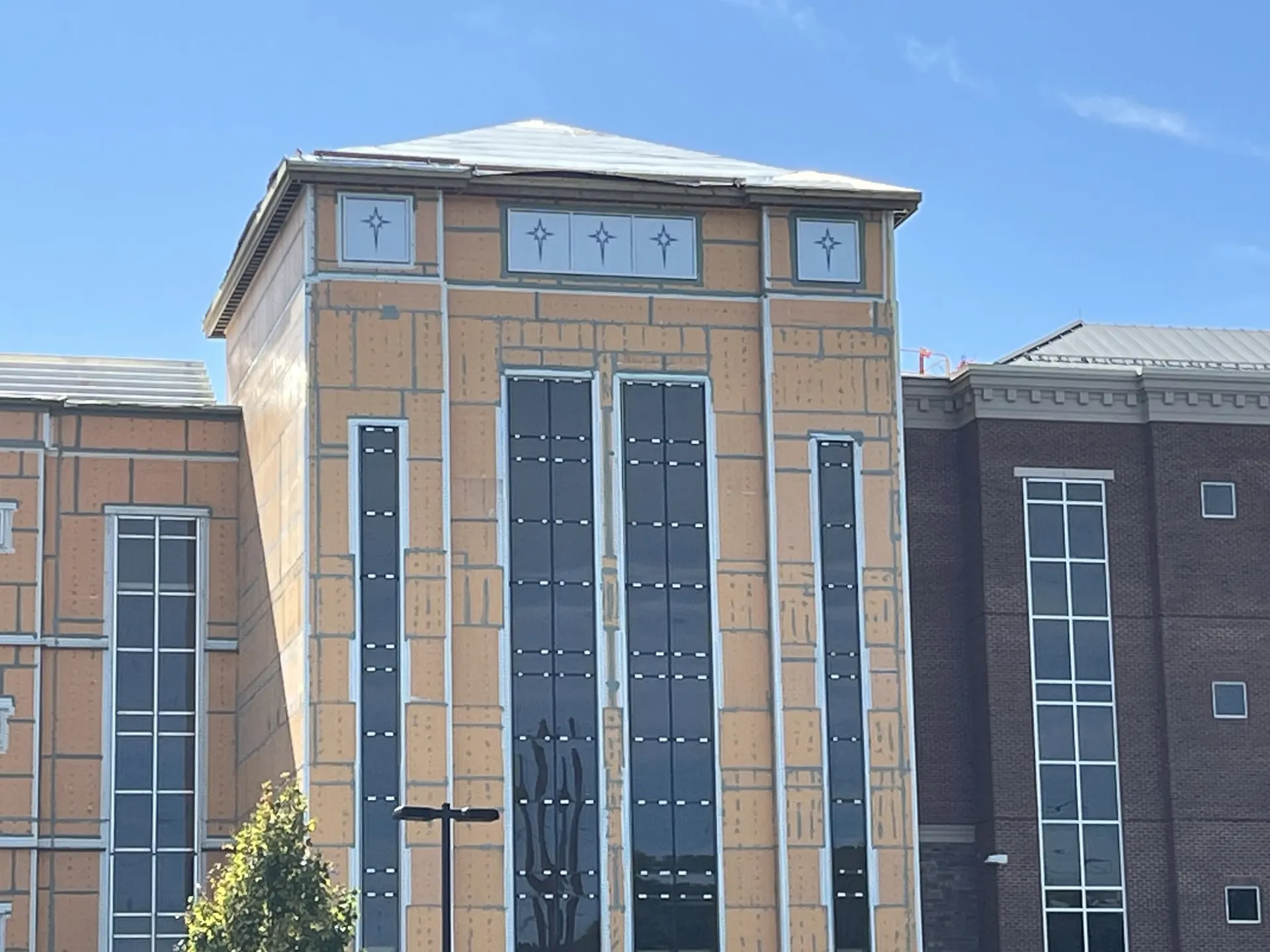 Brick tower facade with tall glazed window bands and decorative mullions on a commercial building