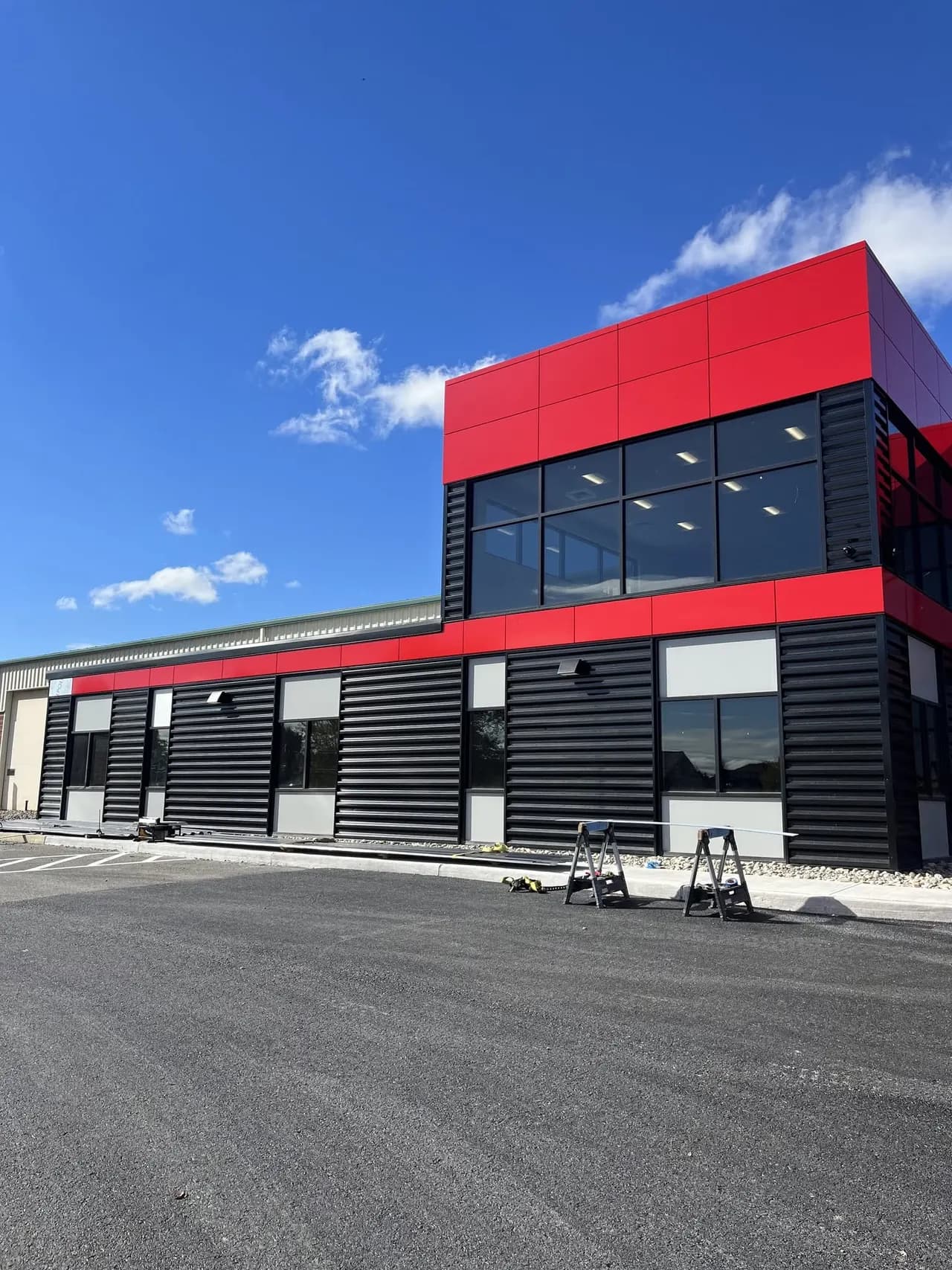 Modern commercial building in black corrugated steel and red panels with new storefront glazing