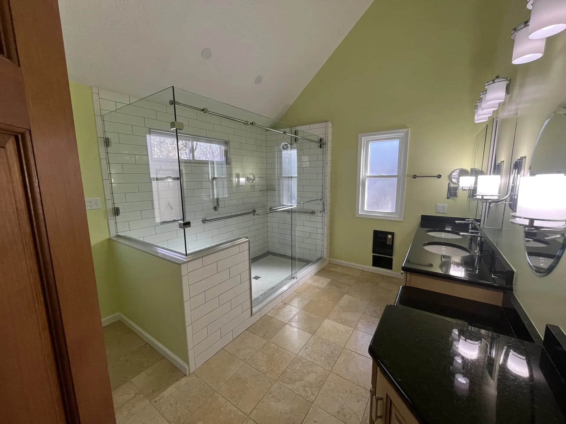 Frameless sliding glass shower enclosure with brushed-nickel hardware over subway tile, real Mesko Glass installation.