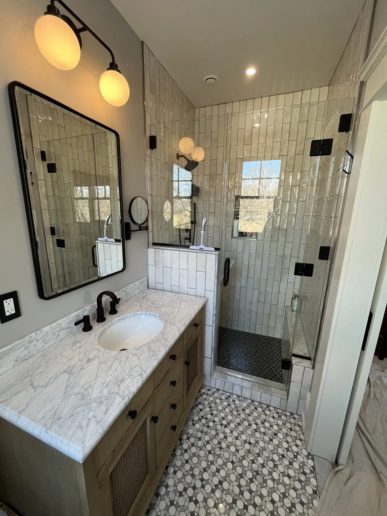 Sliding frameless glass shower enclosure with chrome hardware over vertical tile, real Mesko Glass installation.