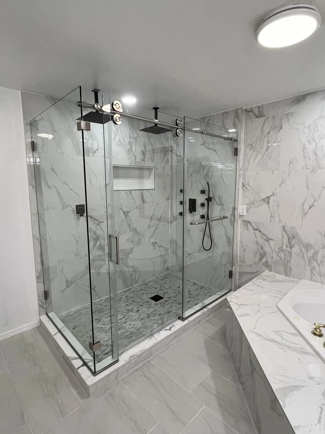 Large frameless glass shower enclosure with brushed-nickel hardware and dual rain shower heads, real Mesko Glass installation.