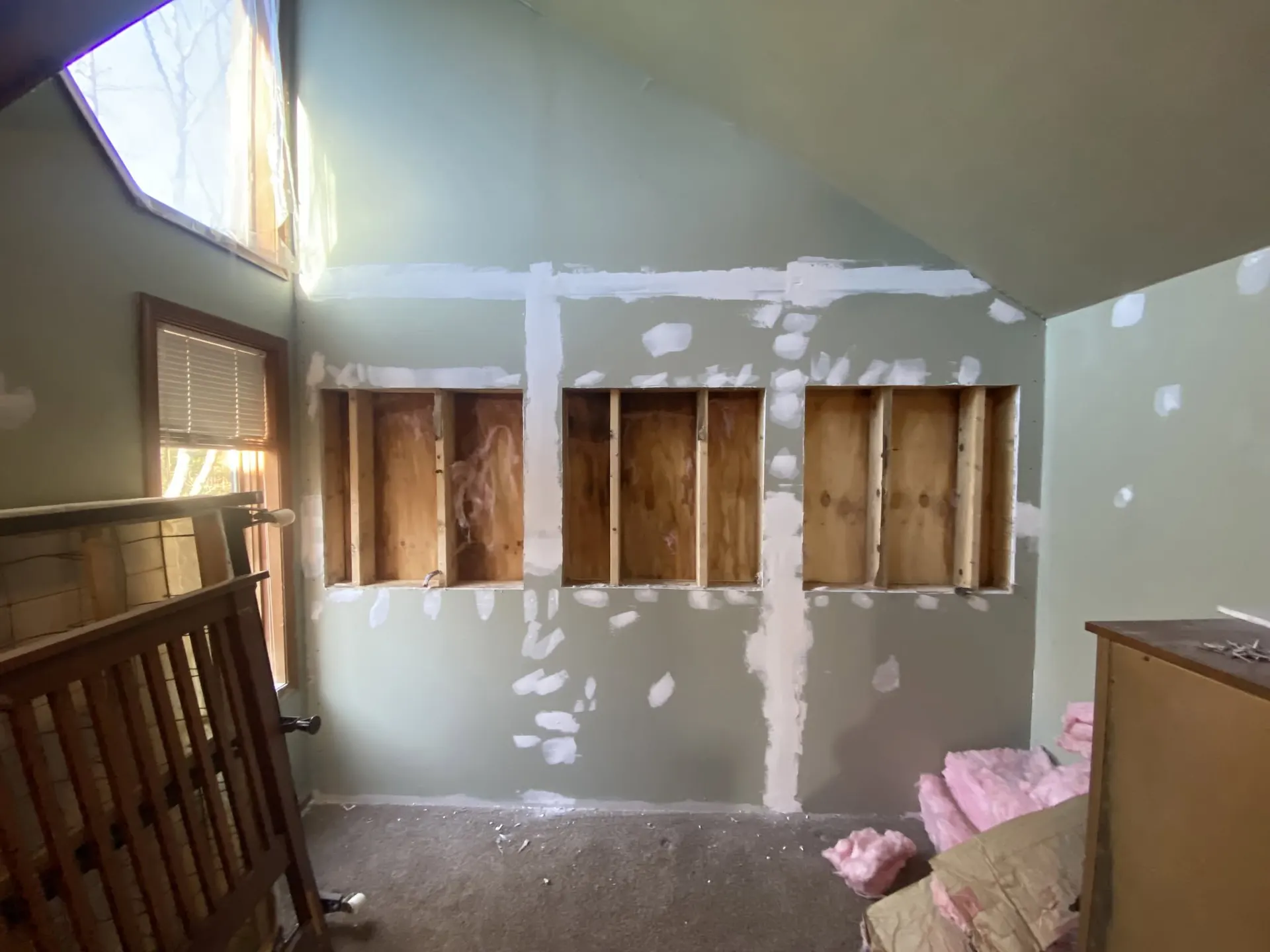 Interior wall opened to the studs for a window installation with pink insulation and a skylight above