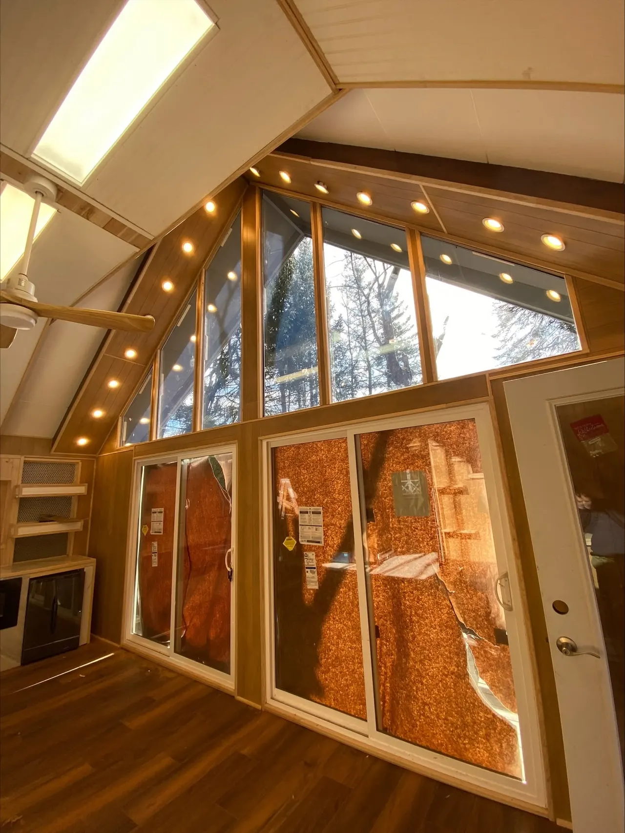 Vaulted A-frame room with new sliding glass patio doors, skylights and recessed lighting along the angled ceiling.