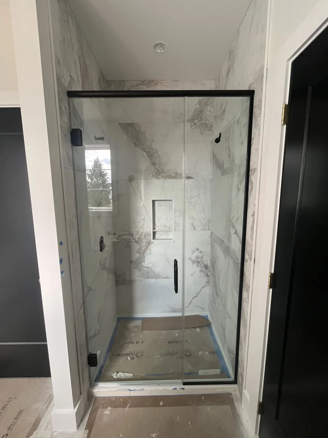 Sliding frameless glass shower enclosure with matte-black hardware, real Mesko Glass installation.
